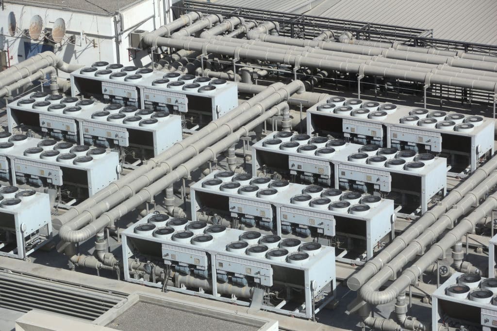 Auf dem Dach des Gebäudes sind Reihen großer industrieller Klimaanlagen mit angeschlossenen Lüftungsöffnungen installiert, die über ein effizientes Spülverfahren verfügen.