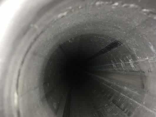 Blick in das Innere eines dunklen, kreisförmigen Metallrohrs, wie es häufig im kommunalen und industriellen Bereich oder bei der Rohrreinigung anzutreffen ist.