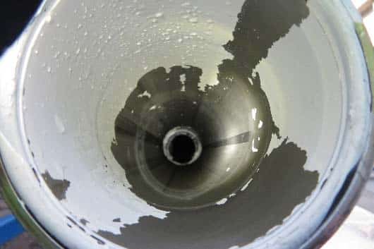 Innenansicht eines Metallrohrs mit abblätternder Farbe und einigen Wassertropfen im Inneren, was auf die Notwendigkeit einer gründlichen Rohrreinigung mit einem wirksamen Spülverfahren hinweist.