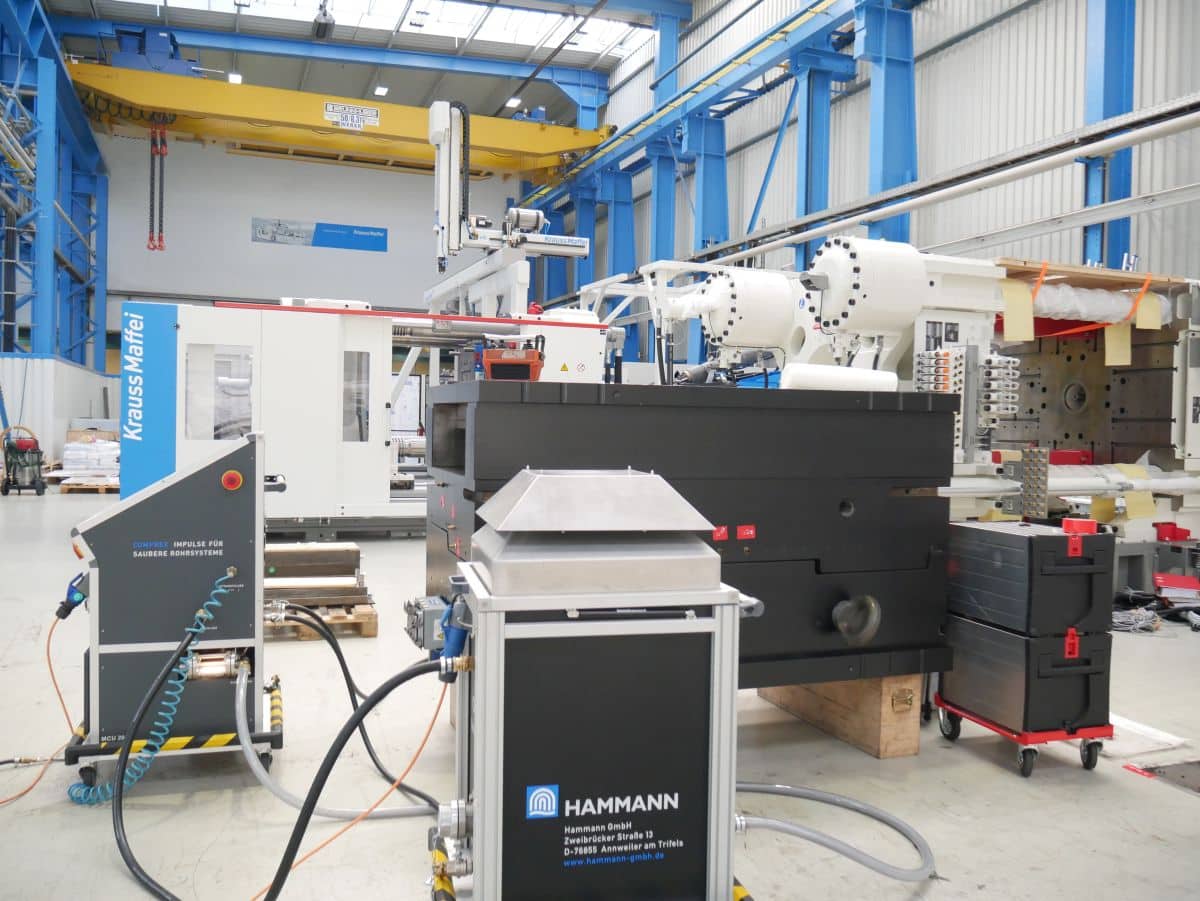 Industrielle Maschinen und Geräte in einer großen, blau-weißen Lagerhalle mit gelbem Kran im Hintergrund, ideal für kommunale Anwendungen.