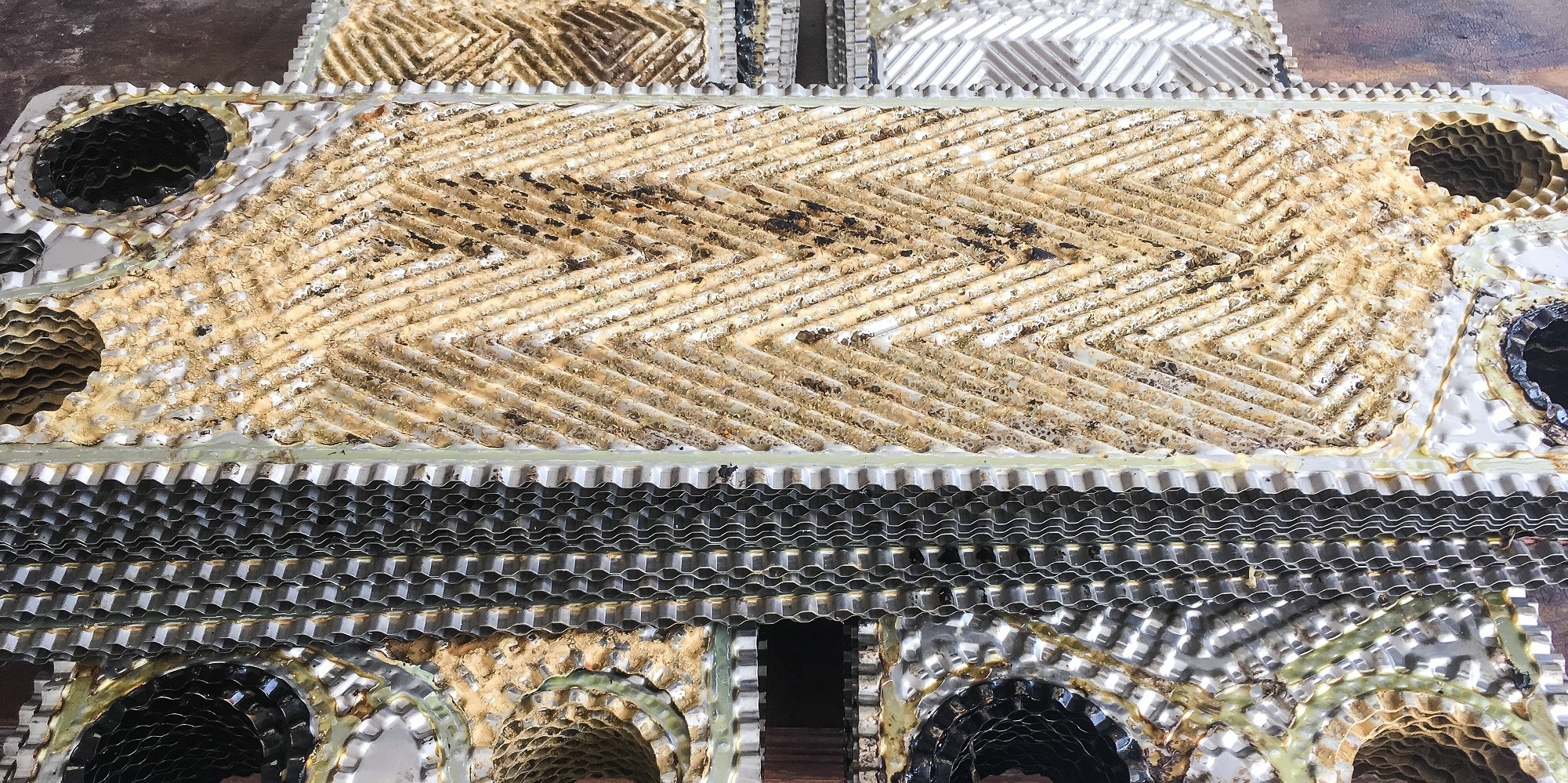 Nahaufnahme eines metallischen Wärmetauschers mit komplizierten Mustern und mehreren wabenartigen Schichten, die höchste Qualität industrieller Ingenieurskunst zur Schau stellen.