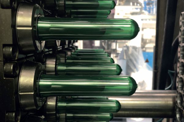 Nahaufnahme von grünen Glasflaschen in einer Reihe auf einem industriellen Produktionsband. Hervorzuheben ist das sorgfältige Spülverfahren, das zur Gewährleistung makelloser Sauberkeit eingesetzt wird.