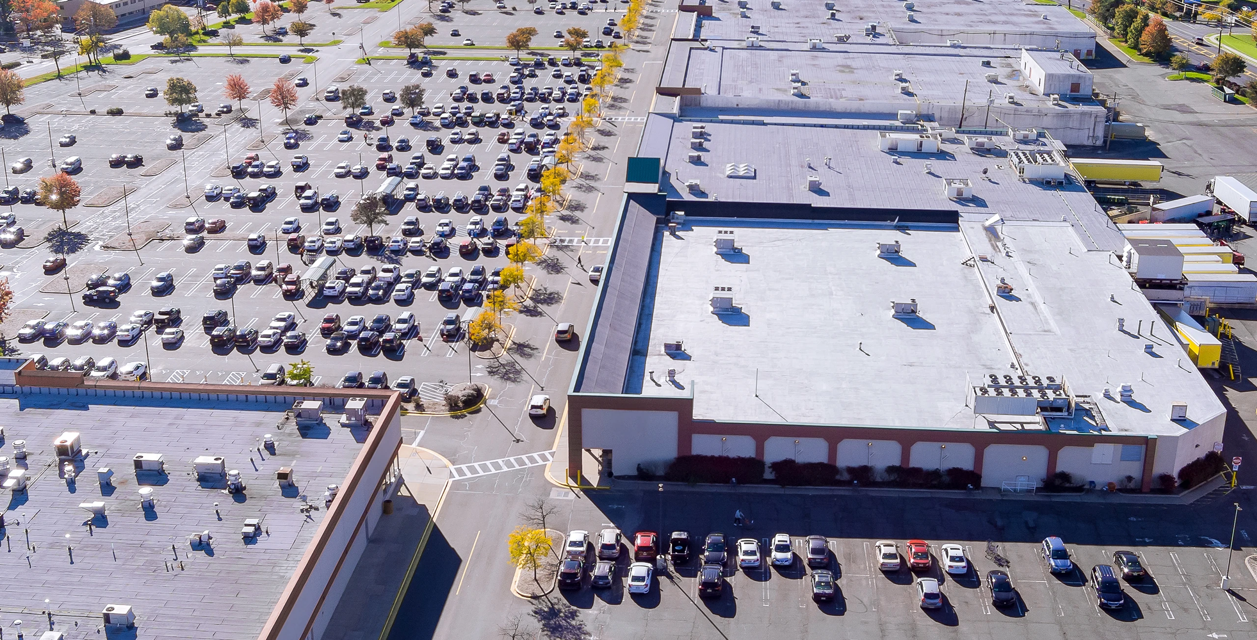 Die Leute gehen durch eine geräumige, sonnendurchflutete Lobby mit deckenhohen Fenstern und einem leeren weißen Banner, das von der Decke hängt – perfekt, um für die örtlichen Dienstleistungen von Gewerbe zu werben.