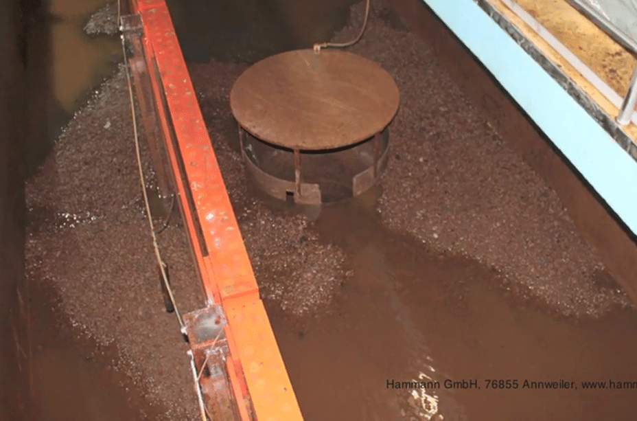 A stationary mechanical component shown amidst what appears to be a wastewater treatment process, with a mixture of water and sediments visible, is often essential for pig cleaning operations.