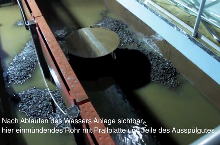 Metallic structure in a rectangular water tank with a central circular disc; text in German at the bottom describes the water system and visible components, including references to pig cleaning processes.